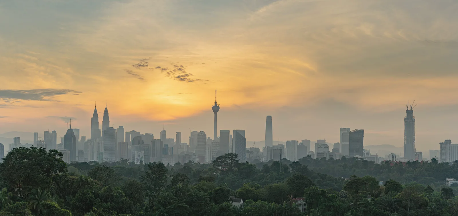 The Kuala Lumpur skyline at golden sunset above the trees